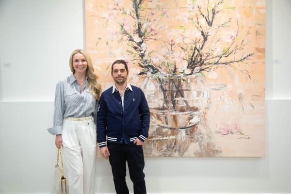 People posing in front of Eric Alfaro's paintings displayed in Carousel Fine Art's Buckhead Village location during the Eric Alfaro exhibition "Spring Reverie."