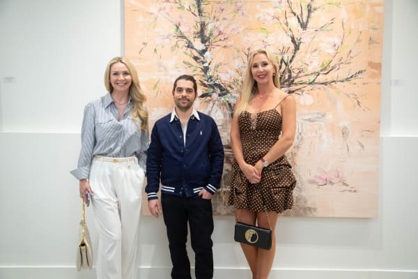 People posing in front of Eric Alfaro's paintings displayed in Carousel Fine Art's Buckhead Village location during the Eric Alfaro exhibition "Spring Reverie."