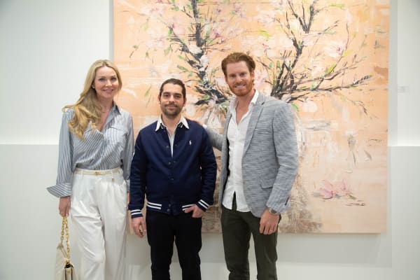 People posing in front of Eric Alfaro's paintings displayed in Carousel Fine Art's Buckhead Village location during the Eric Alfaro exhibition "Spring Reverie."