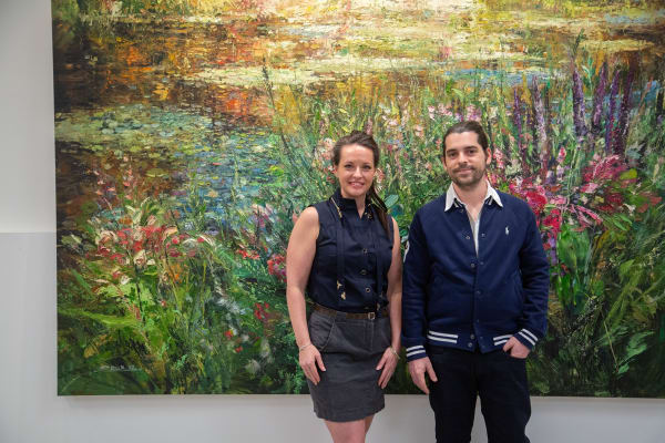 People posing in front of Eric Alfaro's paintings displayed in Carousel Fine Art's Buckhead Village location during the Eric Alfaro exhibition "Spring Reverie."