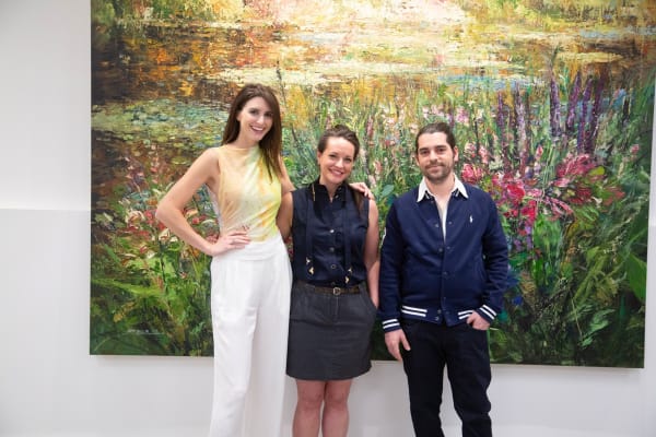 People posing in front of Eric Alfaro's paintings displayed in Carousel Fine Art's Buckhead Village location during the Eric Alfaro exhibition "Spring Reverie."