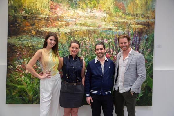 People posing in front of Eric Alfaro's paintings displayed in Carousel Fine Art's Buckhead Village location during the Eric Alfaro exhibition "Spring Reverie."