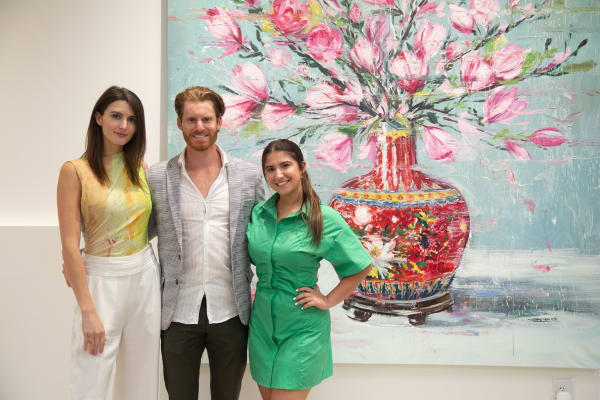People posing in front of Eric Alfaro's paintings displayed in Carousel Fine Art's Buckhead Village location during the Eric Alfaro exhibition "Spring Reverie."