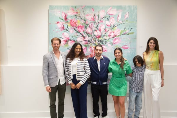 People posing in front of Eric Alfaro's paintings displayed in Carousel Fine Art's Buckhead Village location during the Eric Alfaro exhibition "Spring Reverie."