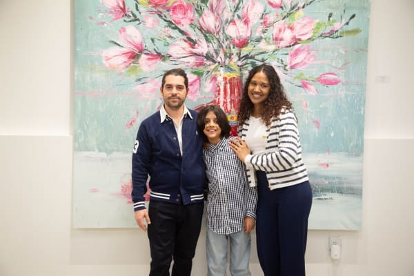People posing in front of Eric Alfaro's paintings displayed in Carousel Fine Art's Buckhead Village location during the Eric Alfaro exhibition "Spring Reverie."