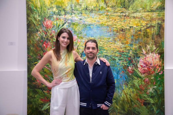 Gallery owner of Carousel Fine Art and artist Eric Alfaro posing in front of Eric Alfaro's paintings displayed in Carousel Fine Art's Buckhead Village location during the Eric Alfaro exhibition "Spring Reverie."