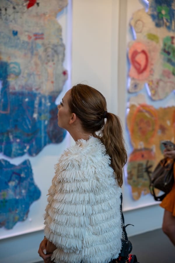 Woman staring at painting displayed at Carousel Fine Art's Miami gallery space for the exhibition, "If These Walls Could Talk."