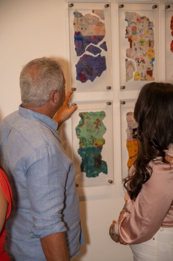 People staring at paintings in Carousel Fine Art's Miami gallery space for the exhibition, "If These Walls Could Talk."