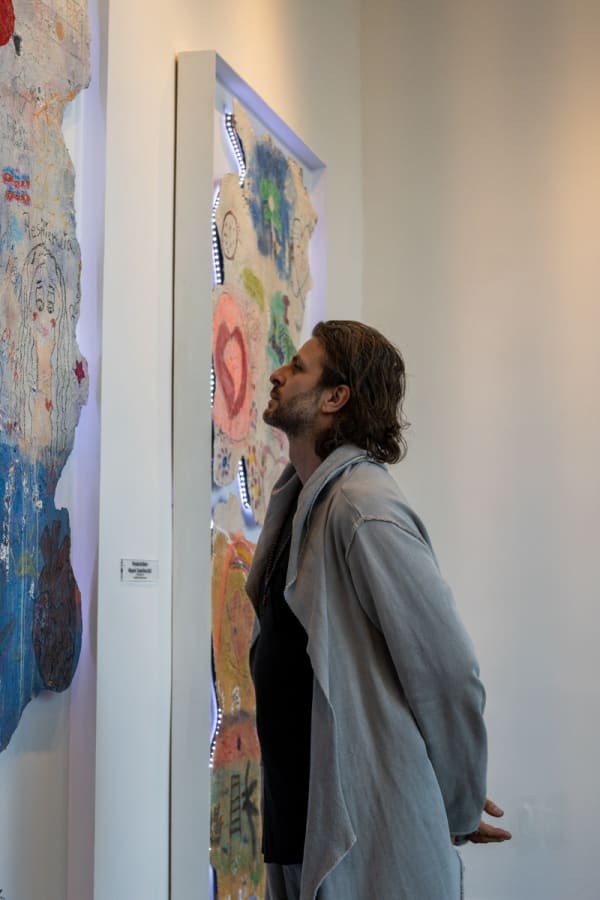 Artist Justin Garcia staring at his paintings in Carousel Fine Art's Miami gallery space for the exhibition, "If These Walls Could Talk."