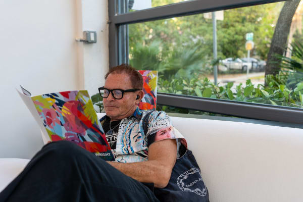 Man looking at book inside Carousel Fine Art's Miami gallery space during Neill Wright's exhibition "Where the Light Gets In."