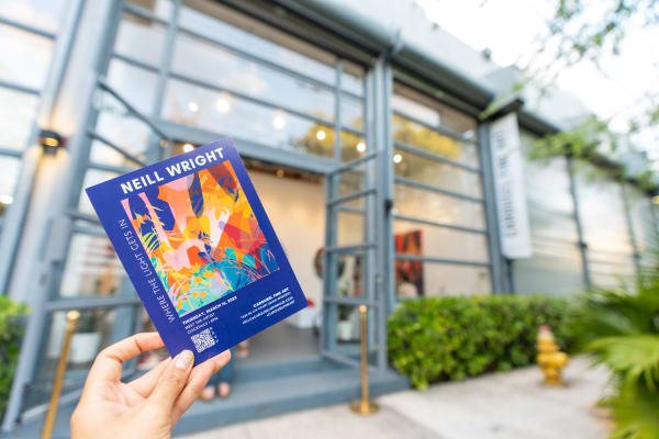 Hand holding booklet outside of Carousel Fine Art's Miami gallery space during Neill Wright's exhibition "Where the Light Gets In."