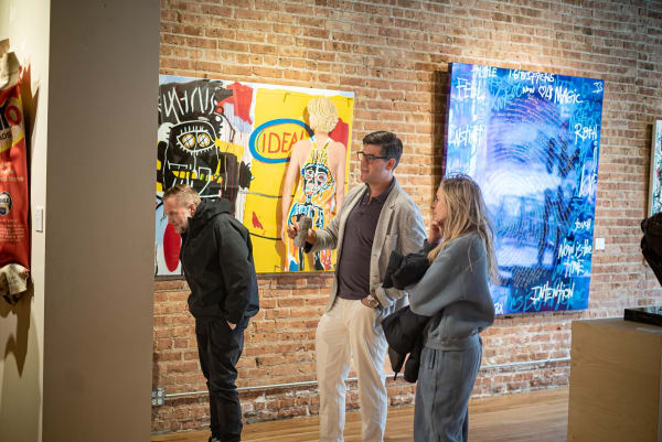 People staring at paintings hanging on wall in Carousel Fine Art's Chicago location during the Chicago Grand Opening.