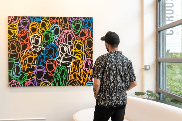 Artist Chance Cooper standing in front of his hanging artworks in Carousel Fine Art's gallery space in Miami, FL during Chance Cooper's Spotlight Exhibition, "Between Me and You."