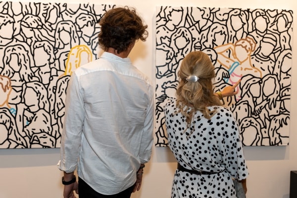People staring at paintings displayed at Carousel Fine Art's gallery space in Miami, FL during Chance Cooper's Spotlight Exhibition, "Between Me and You."