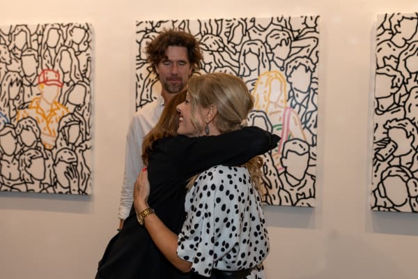 People hugging at Carousel Fine Art's gallery space in Miami, FL during Chance Cooper's Spotlight Exhibition, "Between Me and You."