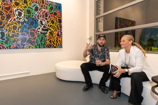 People sitting on couch at Carousel Fine Art's gallery space in Miami, FL during Chance Cooper's Spotlight Exhibition, "Between Me and You."