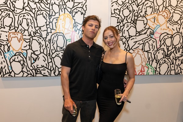 People posing in front of paintings displayed at Carousel Fine Art's gallery space in Miami, FL during Chance Cooper's Spotlight Exhibition, "Between Me and You."