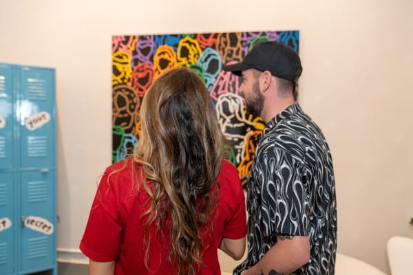 People staring at paintings displayed at Carousel Fine Art's gallery space in Miami, FL during Chance Cooper's Spotlight Exhibition, "Between Me and You."