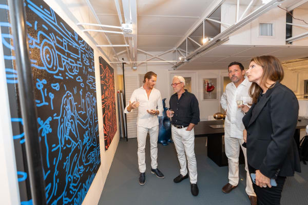 People staring at paintings displayed at Carousel Fine Art's gallery space in Miami, FL during Chance Cooper's Spotlight Exhibition, "Between Me and You."