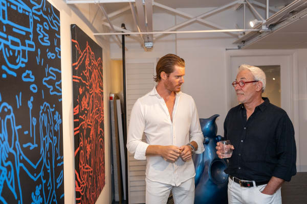 Men next to paintings displayed at Carousel Fine Art's gallery space in Miami, FL during Chance Cooper's Spotlight Exhibition, "Between Me and You."