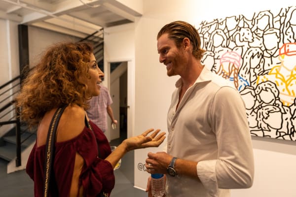 People talking at Carousel Fine Art's gallery space in Miami, FL during Chance Cooper's Spotlight Exhibition, "Between Me and You."
