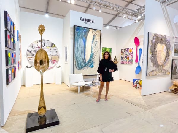 Woman posing at Carousel Fine Art's gallery both at the Hampton's Art Market, 2021.