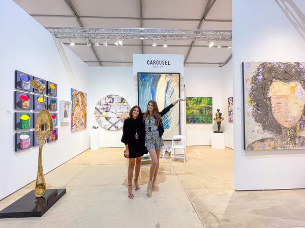 Two women posing at Carousel Fine Art's gallery both at the Hampton's Art Market, 2021.