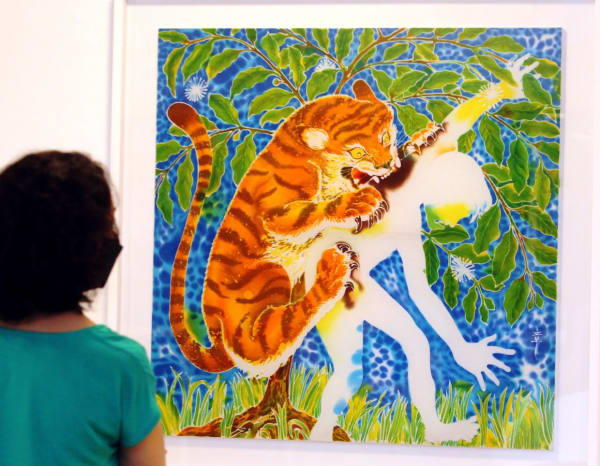 A gallery visitor gets a closer view of Chang's 'Gambir And The Tiger' (batik - remazol dye on cotton cloth, 2022). Photo: The Star/Azlina Abdullah