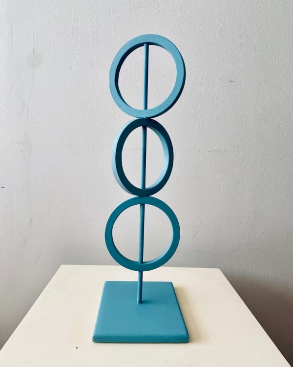 blue steel sculpture with three rings on top of each other representing Mind Body and Spirit.