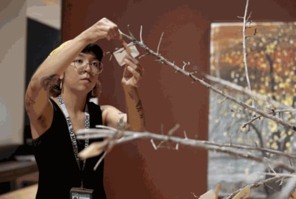 Hood Museum staff attach a visitor’s poem to a dead apple tree, The Emissary, bringing it back to life.