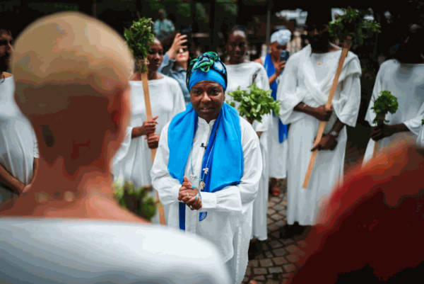 Campos-Pons, in blue, speaks to the “angels” before the beginning of the march at Harlem Art Park on 120th Street. Credit:Graham Dickie/The New York Times