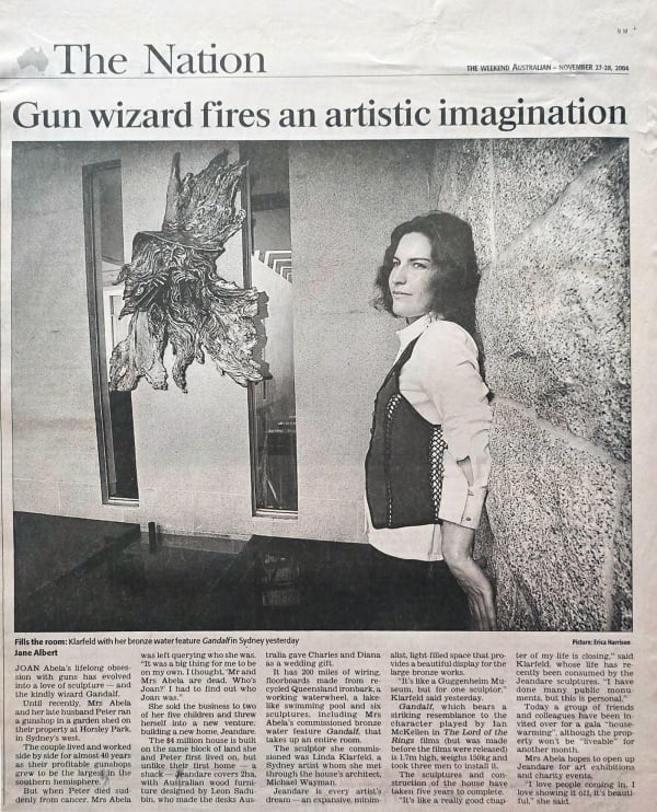 A newspaper article titled "Gun wizard fires an artistic imagination" from The Weekend Australian, published on November 27-28, 2004. The image features sculptor Linda Klarfeld standing beside her bronze water feature titled Gandalf, which hangs on a wall
