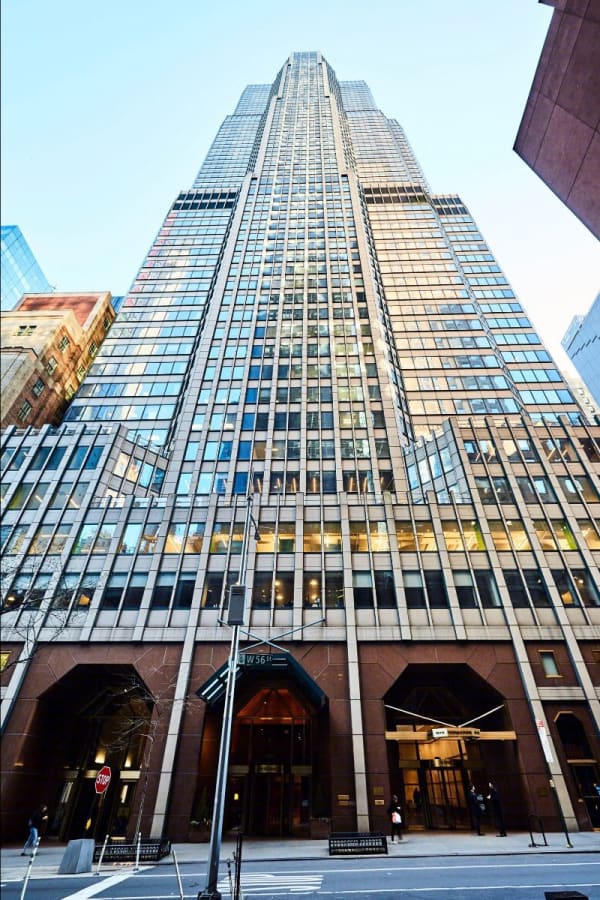 A color photograph of a high-rise office building in New York City, taken from street level looking up