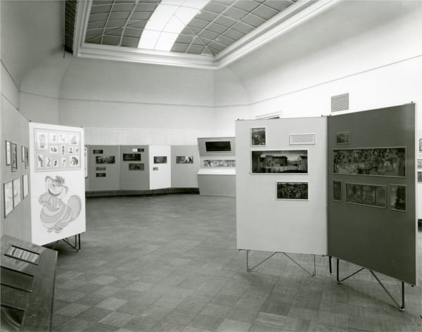 A 1959 black and white photograph of an art installation of Disney Animation drawings and cels hanging on partial display walls