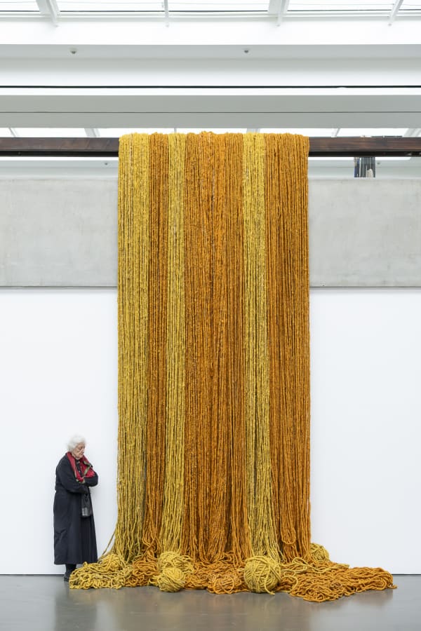 Sheila Hicks neben ihrer Arbeit / Sheila Hicks standing next to her work Aprentizaje de la Victoria, 2008–2016 Wolle/Wool Courtesy die Künstlerin/the artist © VG Bild-Kunst Bonn, 2024 Foto / Photo: Katja Illner