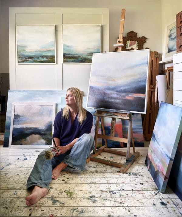 Miranda Carter, captured in her studio surrounded by canvases and brushes, reflecting on the intersection of art and sustainability. Photography rights to Miranda Carter, 2025. Copyright © 2025 Les Bois Magazine. All rights reserved.