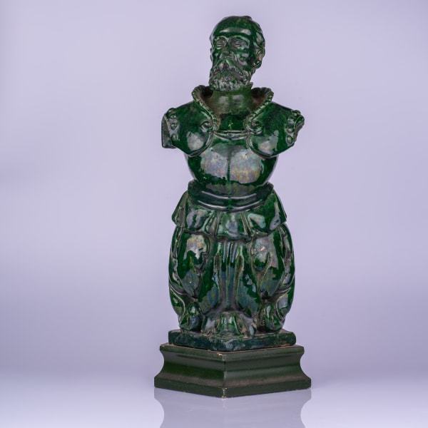 A Continental green glazed terra cotta figural antefix, 19th century