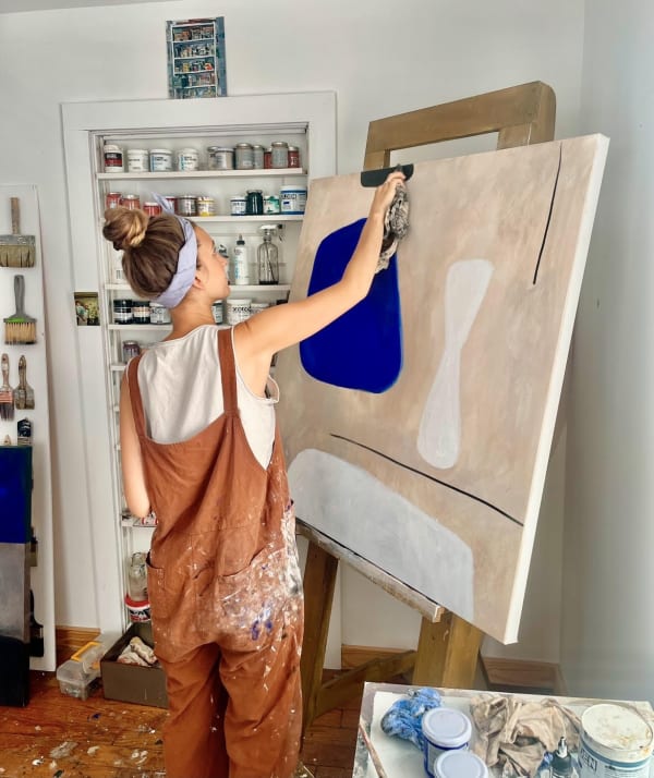 Britt Bates working in her studio. Visible is a beloved painting by her uncle of her grandmother’s art supplies.