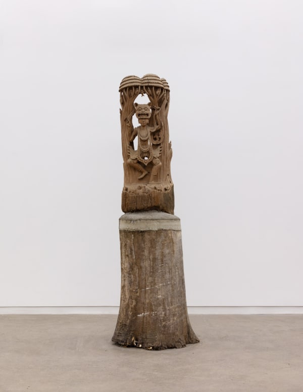 A sculpture of a Bodhisattva from Thailand; early to mid 20th century; carved with a female deity adorned with beaded necklaces and wearing an animal mask in a dancing stance, while small animals and figures occupy the treetops and the ground; carved wood on a custom wood and cement base.