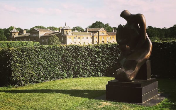 Mother and Child by Henry Moore with our venue - the stables at Houghton Hall in the background