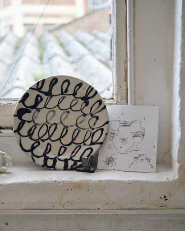 A sliptrailed plate sits slongside drawn designs for caudle cups