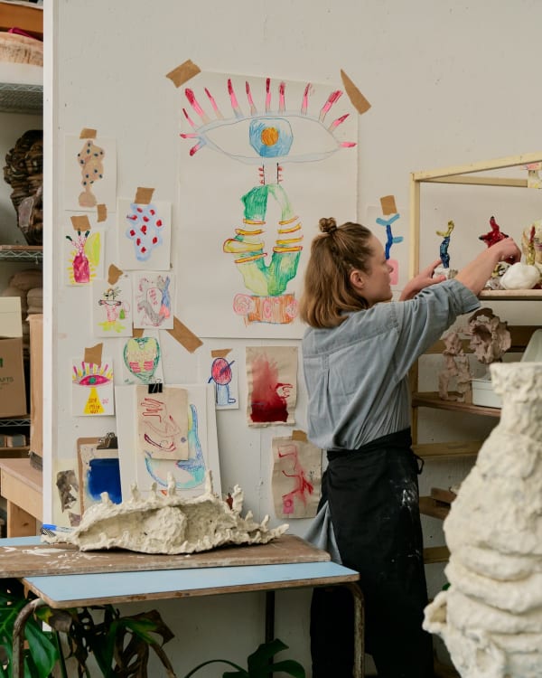 Exploratory sketches are taped to the studio wall to act as inspiration during the making process