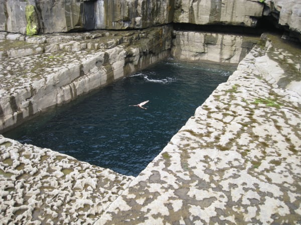 Dorothy Cross, 'Poll Na bPéist', 2008. Photo of a large natural stone pool. A person floats on their back in the middle of the water.