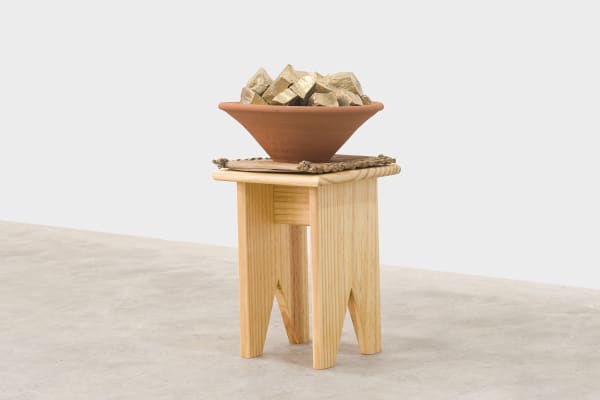 Jaime Lauriano Colonização #2, 2022 apoti, esteira de palha, taboa, alguidar e 28 pedras portuguesas fundidas em latão [apoti, straw mat, cattail, clay bowl, and 28 Portuguese stones cast in brass] 53 x 34 x 34 cm [20 7/8 x 13 3/8 x 13 3/8 in] Ed.: 4/5 + 2 P.A. [A.P.] foto [photo]: Flavio Freire