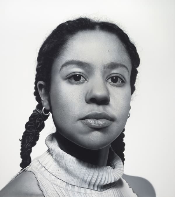 Frontal black and white portrait of a young Black woman in a sleeveless turtleneck.