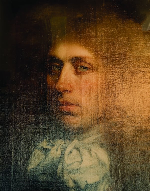 Photograph of a bust-length 17th-century painted portrait of a man staring out at the viewer, seen in raking light so that the texture of the canvas and the brushstrokes are visible but the right side of the picture is obscured by golden glare.