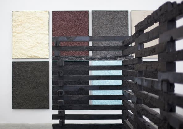 Nick van Woert’s exhibition “No Man’s Land,” at OHWOW Gallery in Los Angeles, includes a construction made of pieces of cast coal slag; in the background are “landscape paintings” that use artificial materials like kitty litter or a mixture of urethane and orange soda.