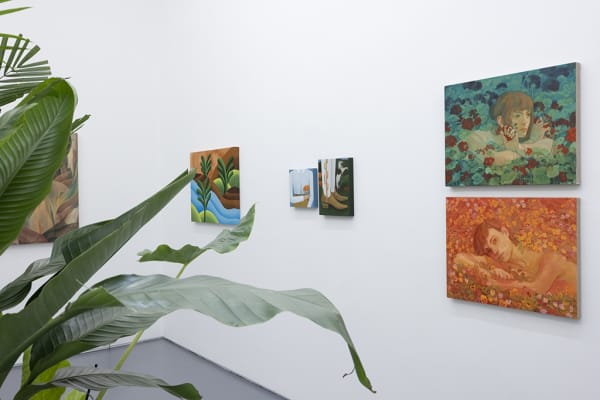 photograph of plant leaves in the foreground and figurative paintings in the background