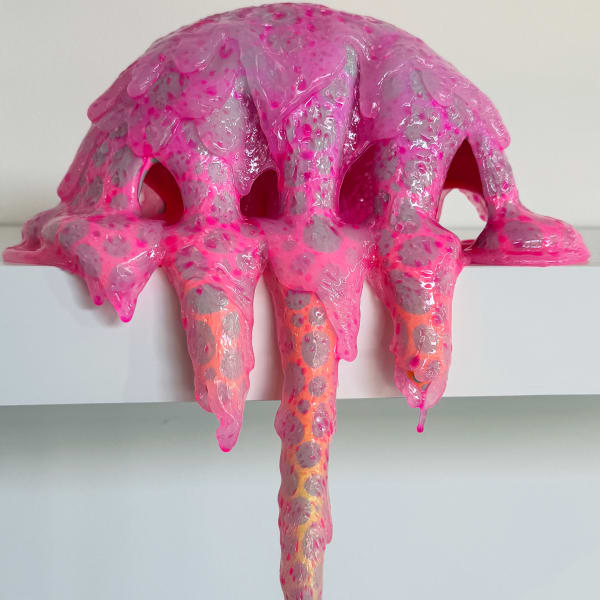 Image of a pink sculpture with grey dots on a white background. The sculpture looks like it's dripping down the side of the mantle it sits on, as it was made by pouring resin and acrylic paint over a crescent shape of polyurethane foam.