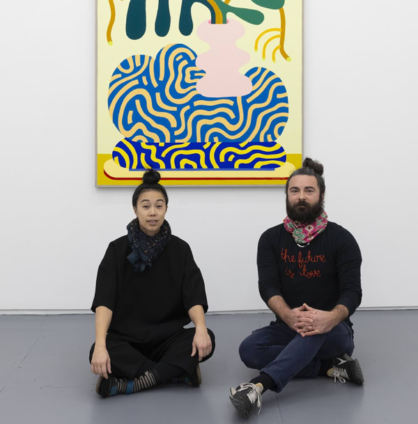 photo of artist duo CHIAOZZA sitting on the floor in front of their painting